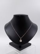 A 750 STAMPED PRECIOUS WHITE METAL DIAMOND PENDANT SUSPENDED ON A 14K STAMPED WHITE METAL CHAIN. THE