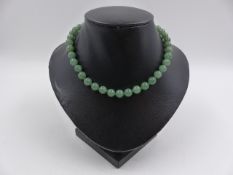 A UNIFORM STRING OF KNOTTED GREEN JADE BEADS APPROXIMATELY 7.5mm, APPROXIMATE WEIGHT 32.2grms.