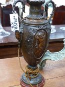 A PAIR OF FRENCH PATINATED METAL TWIN HANDLED URNS WITH FIGURAL DECORATION ON MARBLE BASES NOW