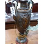 A PAIR OF FRENCH PATINATED METAL TWIN HANDLED URNS WITH FIGURAL DECORATION ON MARBLE BASES NOW