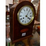 AN EDWARDIAN INLAID MAHOGANY ARCH FORM MANTLE CLOCK WITH BRASS BRACKET FEET.