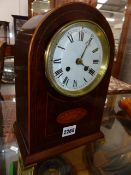 AN EDWARDIAN INLAID MAHOGANY ARCH FORM MANTLE CLOCK WITH BRASS BRACKET FEET.