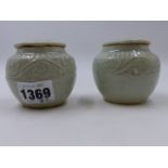 A NEAR PAIR OF EARLY CHINESE CELADON COVERED JARLETS EACH DECORATED WITH SCROLLING BANDS. H.6.5cms.