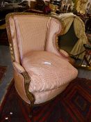 A FRENCH CARVED GILTWOOD WING BACK ARMCHAIR WITH SCROLL FORM FRAME AND FEATHER LOOSE CUSHIONS.