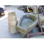 A HORSESHOE FORM STONE TROUGH, ANOTHER TROUGH AND A STADDLE STONE WITH TOP.
