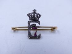 A DIAMOND AND RUBY SET YELLOW METAL PIN, FORMED IN THE LETTER E ENTWINED WITH A NUMBER 7, A GIFT FOR