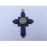 A EARLY 20th CENTURY BLUE GLASS AND ENAMEL COPPER CRUCIFORM PENDANT. MEASUREMENTS 7.5cms X 5.3cms.