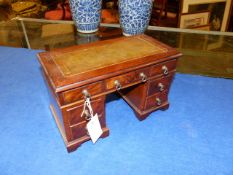 AN ANTIQUE MINIATURE MAHOGANY AND WALNUT PEDESTAL DESK FORM JEWELLERY BOX WITH RISING TOP OVER