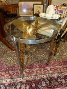 A CONTEMPORARY POLISHED STEEL AND GLASS OCCASIONAL TABLE INSET WITH BRONZE BOAT PROPELLOR.