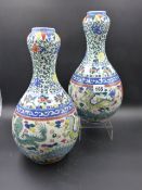 A PAIR OF ORIENTAL GARLIC NECK VASES DECORATED WITH DRAGONS AND BANDS OF SCROLLING FOLIAGE. H.