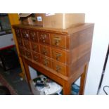 A BANK OF FIFTEEN OAK FILE DRAWERS RAISED ON SQUARE TAPERED LEG. W.84 x H.115cms.