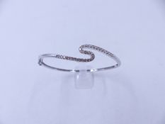 A WHITE METAL (TESTS AS GOLD) DIAMOND HINGED BANGLE COMPLETE WITH TWO FIGURE OF EIGHT SAFETY CLASPS.