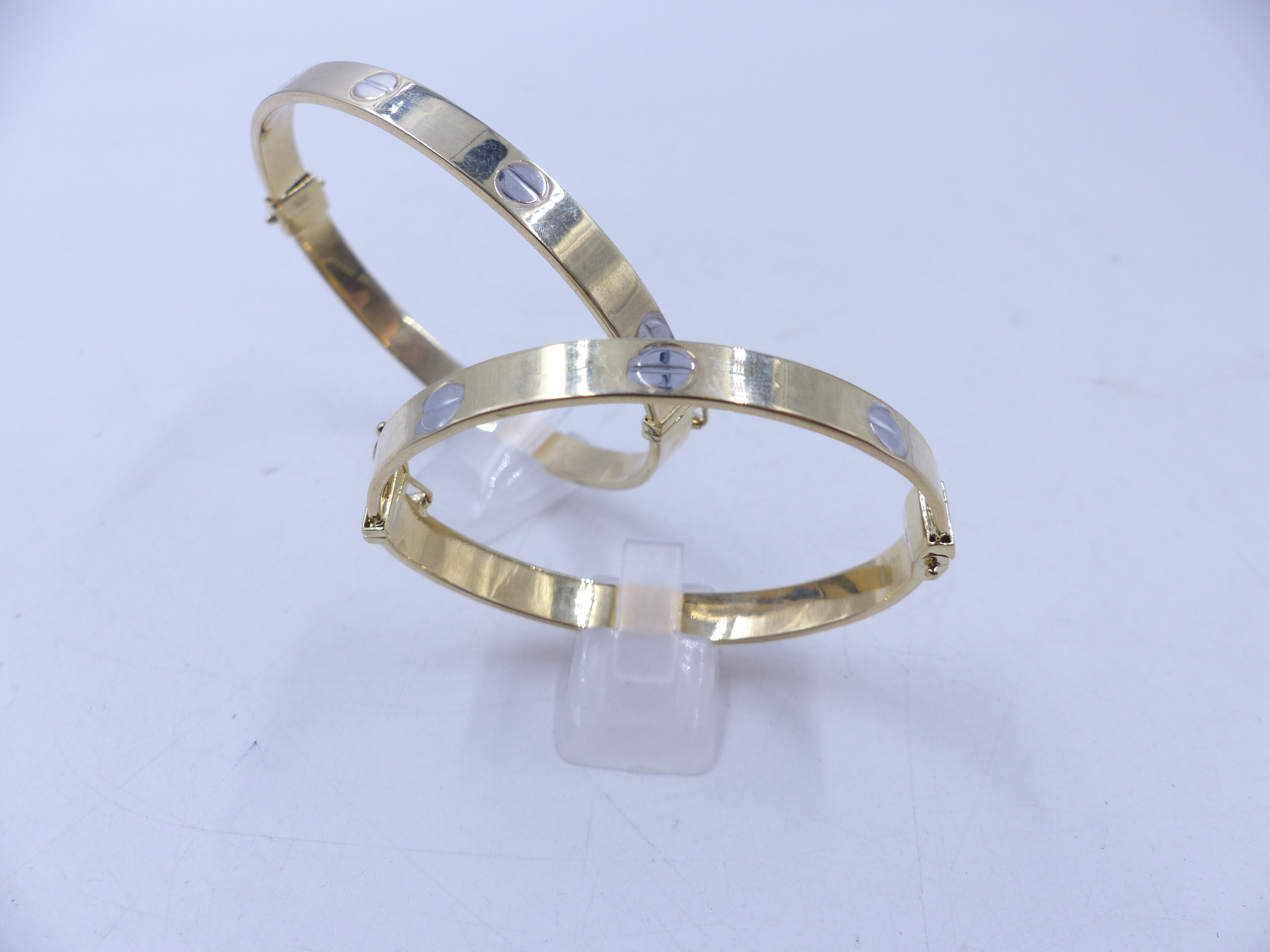 A MATCHING PAIR OF HINGED 9ct CARTIER STYLE BANGLES, ONE ADULT SIZE AND ONE CHILDS SIZE. TOTAL GROSS