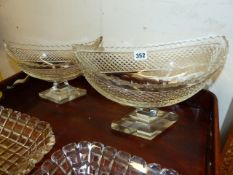 AN IRISH NAVETTE CUT GLASS SHAPED PEDESTAL DISH. L.30cms. H.21cms A SIMILAR SMALLER DISH, L.25cms.