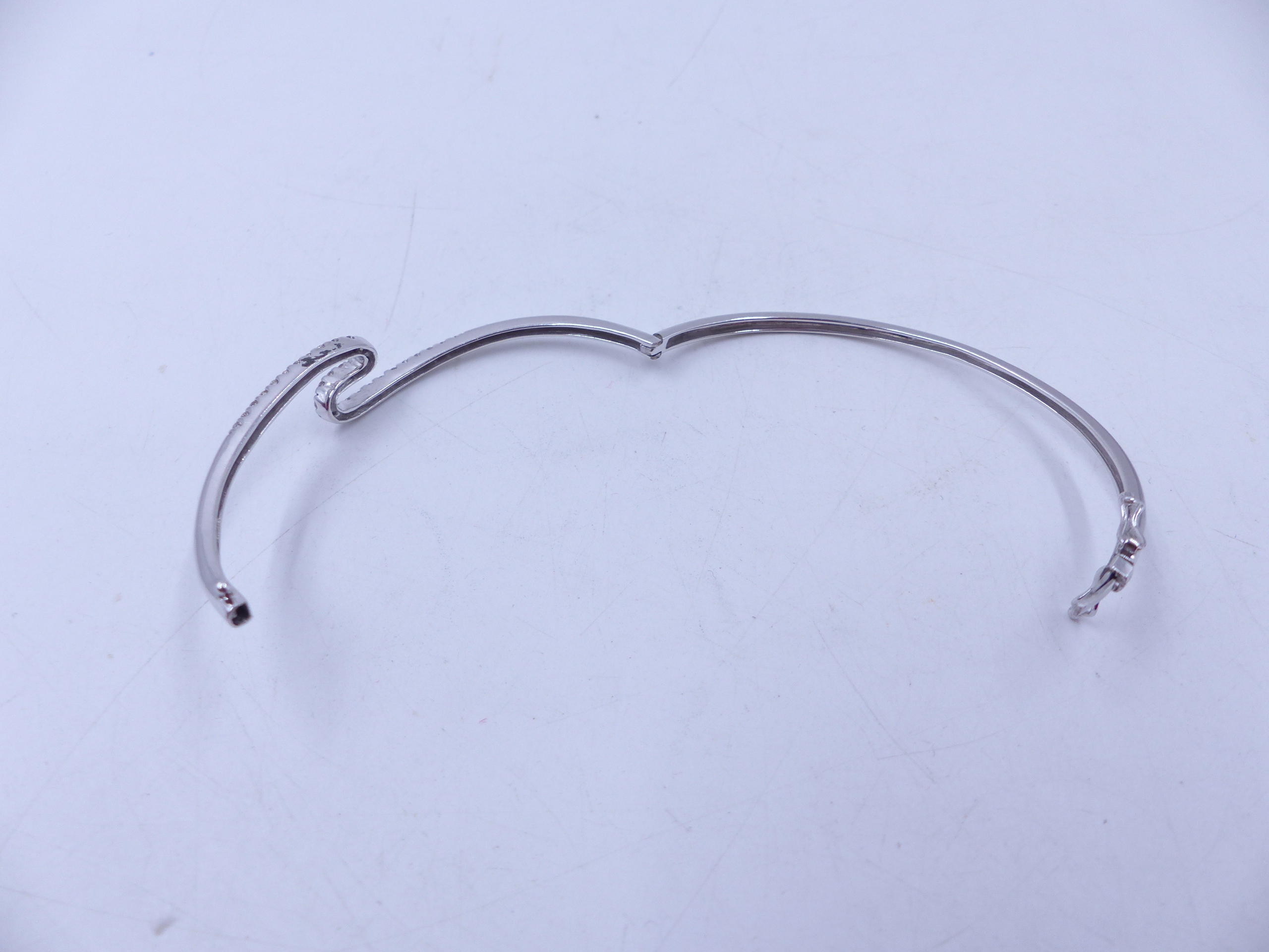 A WHITE METAL (TESTS AS GOLD) DIAMOND HINGED BANGLE COMPLETE WITH TWO FIGURE OF EIGHT SAFETY CLASPS. - Image 4 of 6