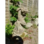 AN OLD WEATHERED COMPOSITE STONE GARDEN FIGURE OF A PUTTI WITH FISH.