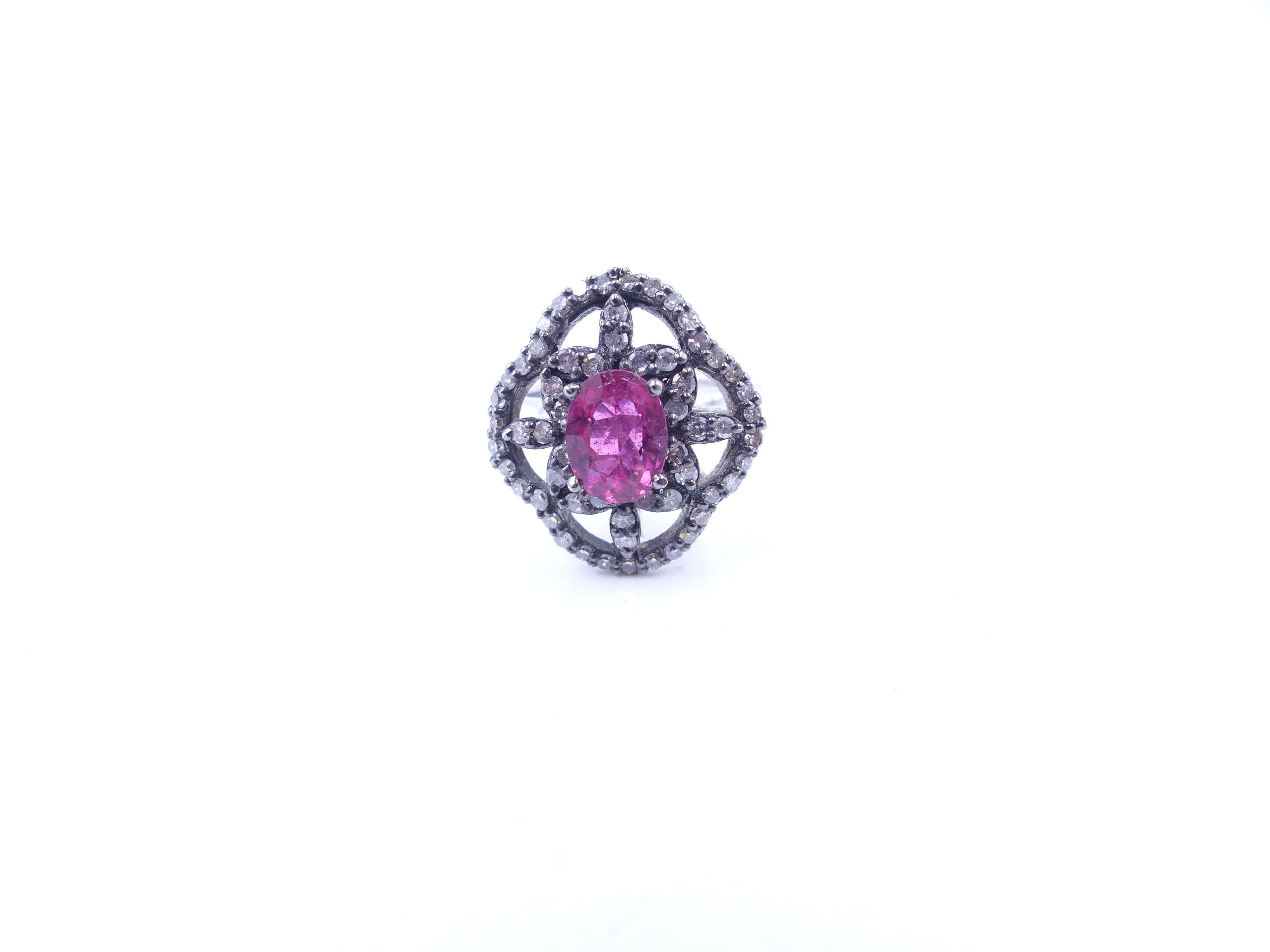 A PINK TOURMALINE AND DIAMOND OPEN WORK FILIGREE RING SET IN A WHITE METAL MOUNT,THE CENTRAL PINK