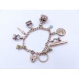 A 625 STAMPED 15ct GOLD CURB CHAIN CHARM BRACELET COMPLETE WITH A 9ct PADLOCK AND ELEVEN VARIOUS