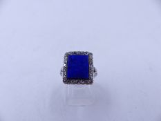 AN 18ct STAMPED WHITE METAL RING SET WITH A CENTRAL LAPIS LAZULI AND A HALO OF OLD CUT DIAMONDS.