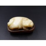 A CHINESE CARVED JADE SMALL FIGURE OF A PUPPY ON A HARDWOOD BASE. L.4.5cms.