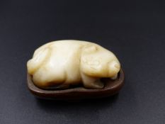 A CHINESE CARVED JADE SMALL FIGURE OF A PUPPY ON A HARDWOOD BASE. L.4.5cms.