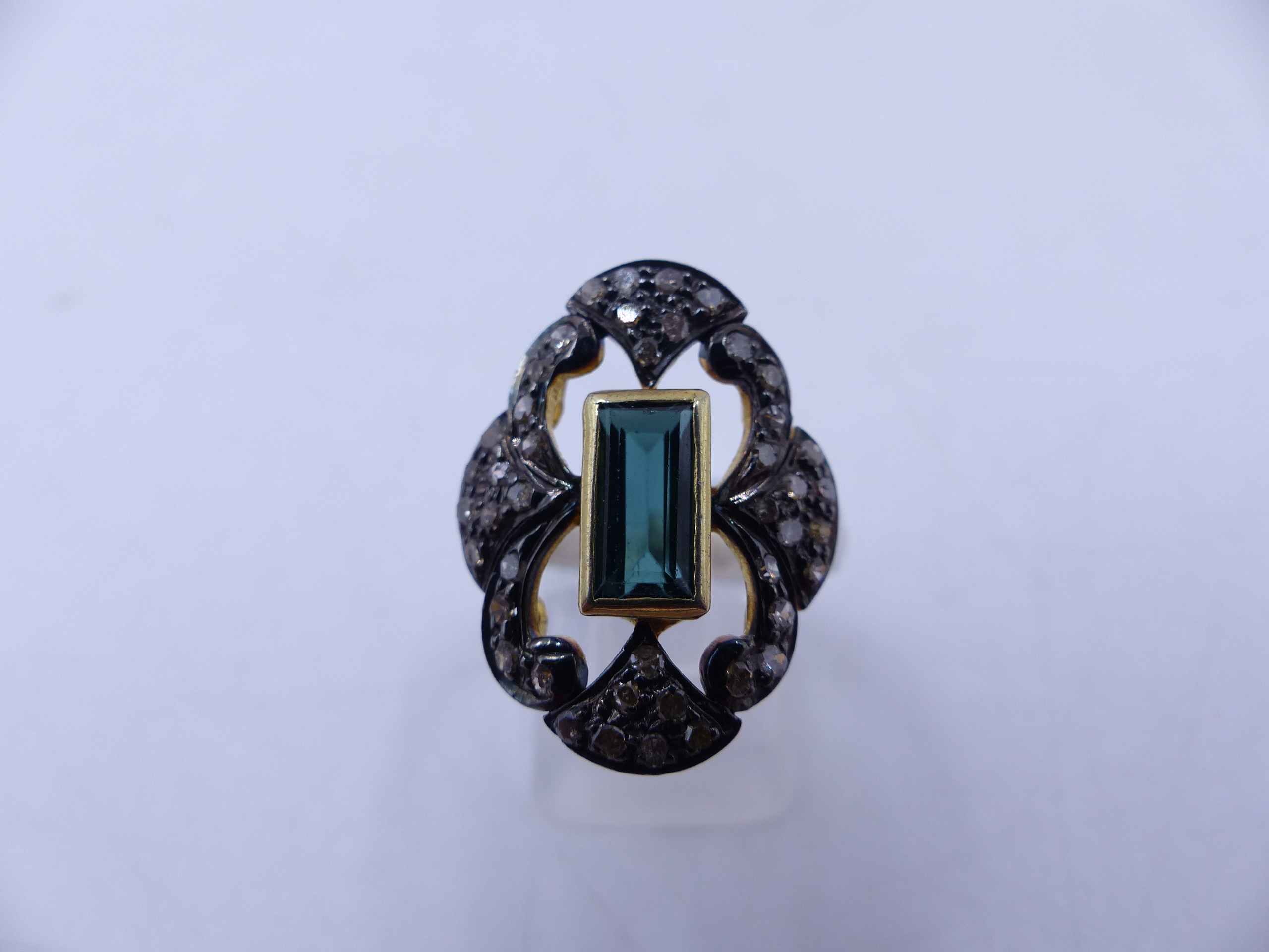 A GREEN TOURMALINE AND FILIGREE SET DIAMOND RING. THE CENTRAL GREEN TOURMALINE IS AN ELONGATED
