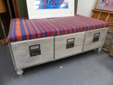 A LARGE LIMED OAK LOW STOOL FITTED WITH THREE DEEP DRAWERS. W.133 x D.82 x H.51cms.