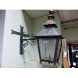 AN ANTIQUE COPPER OUTSIDE LANTERN ON WROUGHT IRON WALL BRACKET. H.90cms.