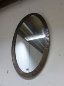 AN ARTS AND CRAFTS BRASS FRAMED OVAL WALL MIRROR.