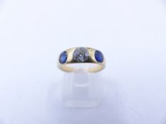 AN 18 STAMPED YELLOW GOLD SAPPHIRE AND DIAMOND THREE STONE TRADITIONAL GYPSY-SET RING. THE CENTRE