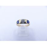 AN 18 STAMPED YELLOW GOLD SAPPHIRE AND DIAMOND THREE STONE TRADITIONAL GYPSY-SET RING. THE CENTRE