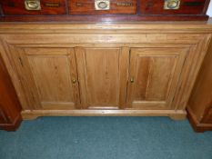 A LATE VICTORIAN PINE TWO DOOR DRESSER BASE OR SIDE CABINET ON PLINTH BASE. W.145 x H.82cms.
