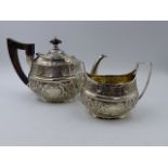 A VICTORIAN SILVER CHASED AND HALLMARKED TEAPOT AND SUGAR, ENGRAVED ON ONE SIDE 1873-1898 AND ON THE