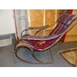 AN ANTIQUE WROUGHT IRON AND BRASS ROCKING CHAIR WITH KELIM SLING UPHOLSTERED SEAT, AFTER A DESIGN BY