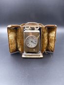 A SILVER CASED CARRIAGE OR DRESSING TABLE CLOCK WITH ORIGINAL PROTECTIVE LEATHER CASE.