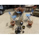 A SMALL PAINTED PATIO TABLE WITH TWO CHAIRS AND VARIOUS PLANT POTS.