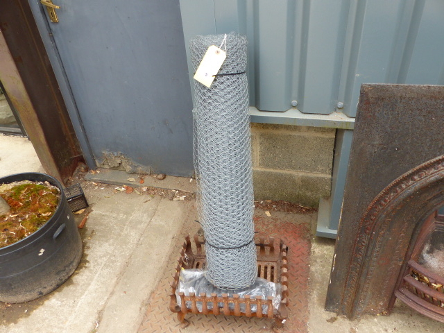 A CAST IRON FIRE BASKET AND A ROLL OF CHICKEN WIRE.