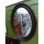 A LARGE OVAL WALL MIRROR.