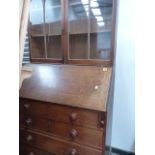 A GEORGIAN OAK BUREAU WITH ASSOCIATED BOOKCASE OVER.