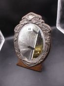 A SILVER MOUNTED OVAL BEVELLED GLASS MIRROR ON AN OAK EASEL BACKED STAND. BIRMINGHAM 1904. H.31.