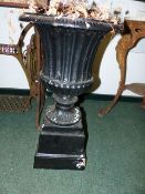 A PAIR OF PAINTED CAST IRON FLUTED CAMPAGNA FORM GARDEN URNS ON STEPPED PLINTH BASES. H.69cms.