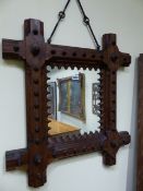 A VICTORIAN GOTHIC PITCH PINE FRAMED WALL MIRROR WITH WROUGHT IRON SUSPENSION. 62 x 68cms.