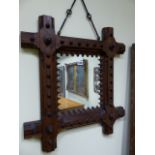 A VICTORIAN GOTHIC PITCH PINE FRAMED WALL MIRROR WITH WROUGHT IRON SUSPENSION. 62 x 68cms.