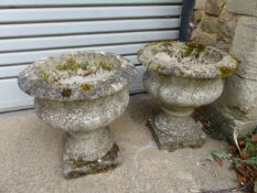 A PAIR OF COMPOSITE STONE GARDEN URNS ON SQUARE PLINTH BASES. (2)