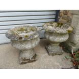 A PAIR OF COMPOSITE STONE GARDEN URNS ON SQUARE PLINTH BASES. (2)