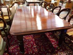 A VICTORIAN MAHOGANY WIND OUT EXTENDING DINING TABLE ON TURNED REEDED LEGS WITH BRASS CASTORS