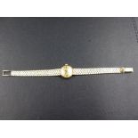 A LADIES GOLD OMEGA WRIST WATCH, STAMPED 585 AND TESTED AS 14ct. ON A BRICK STYLE BRACELET WITH A