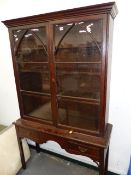 A GEORGIAN AND LATER OAK GLAZED BOOKCASE ON STAND WITH TWO FRIEZE DRAWERS AND CHAMFERED SQUARE