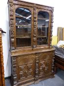A 19th.C.CARVED OAK BOOKCASE WITH GLAZED UPPER SECTION OVER TWO GEOMETRIC CARVED PANEL DOORS. W.