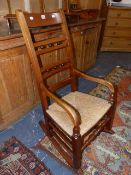 A LATE VICTORIAN ROCKING CHAIR WITH LADDER BACK AND RUSH SEAT.